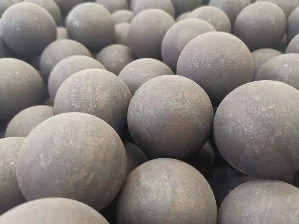 Close-up of forged steel grinding balls with rough surfaces, used in ball mills and SAG mills for industrial ore processing.