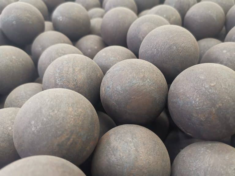 Close-up of forged steel grinding balls with rough surfaces, used in ball mills and SAG mills for industrial ore processing.