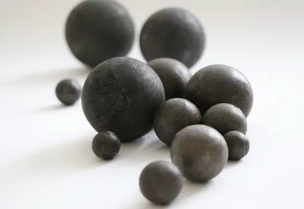 Boules de broyage forgées de différents diamètres disposées sur un fond blanc, destinées à une utilisation dans des broyeurs industriels.