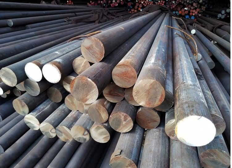 Steel grinding rods neatly stacked, used in industrial mills for crushing ores and other materials.