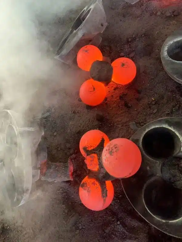 Bolas de aço fundido incandescentes em processo de moldagem, mostrando a alta temperatura da fundição.