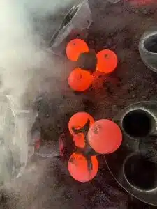 Molten steel balls glowing during the molding process, showing the high temperature of the casting.
