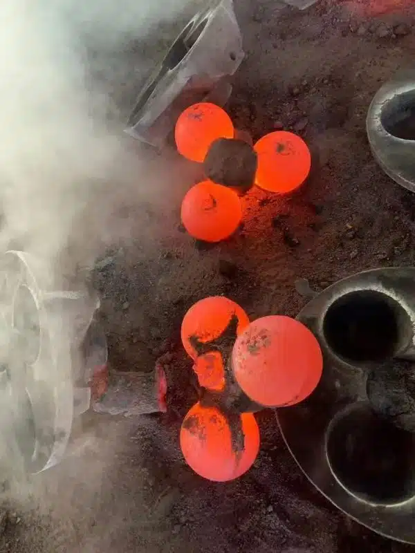 Molten steel balls glowing during the molding process, showing the high temperature of the casting.
