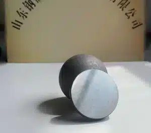 Cross-section of a forged steel grinding ball, showing the inner microstructure, with Shandong Gangyan logo in the background
